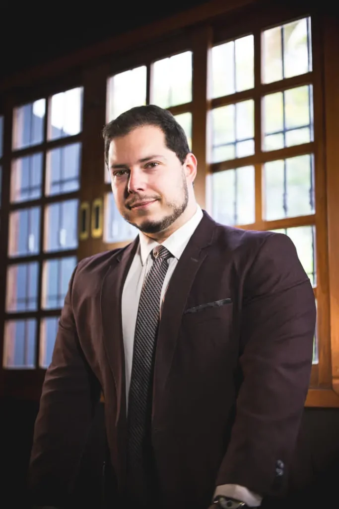 André Salles, advogado de Família e Sucessões, de terno diante de janelas de madeira